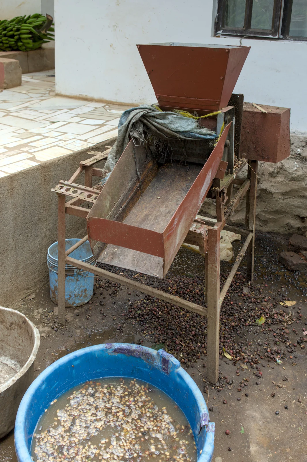 Koffieontpulpmachine naast een wasbak op een boerderij in Tanzania